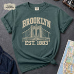 Blue Spruce Comfort Colors t-shirt featuring a vintage Brooklyn Bridge graphic with bold Brooklyn text and “Est. 1883” lettering.