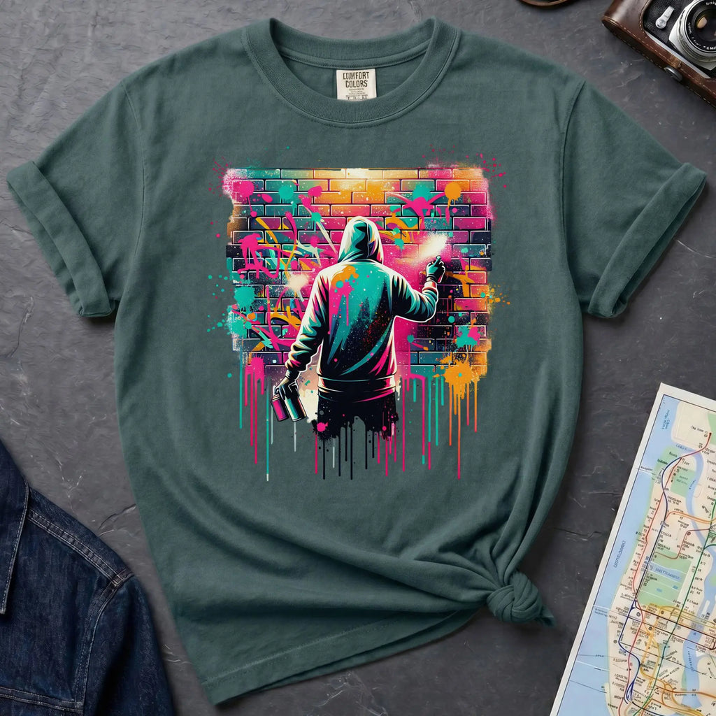 Blue Spruce t-shirt with a graphic of a person spray painting a colorful mural on a brick wall.