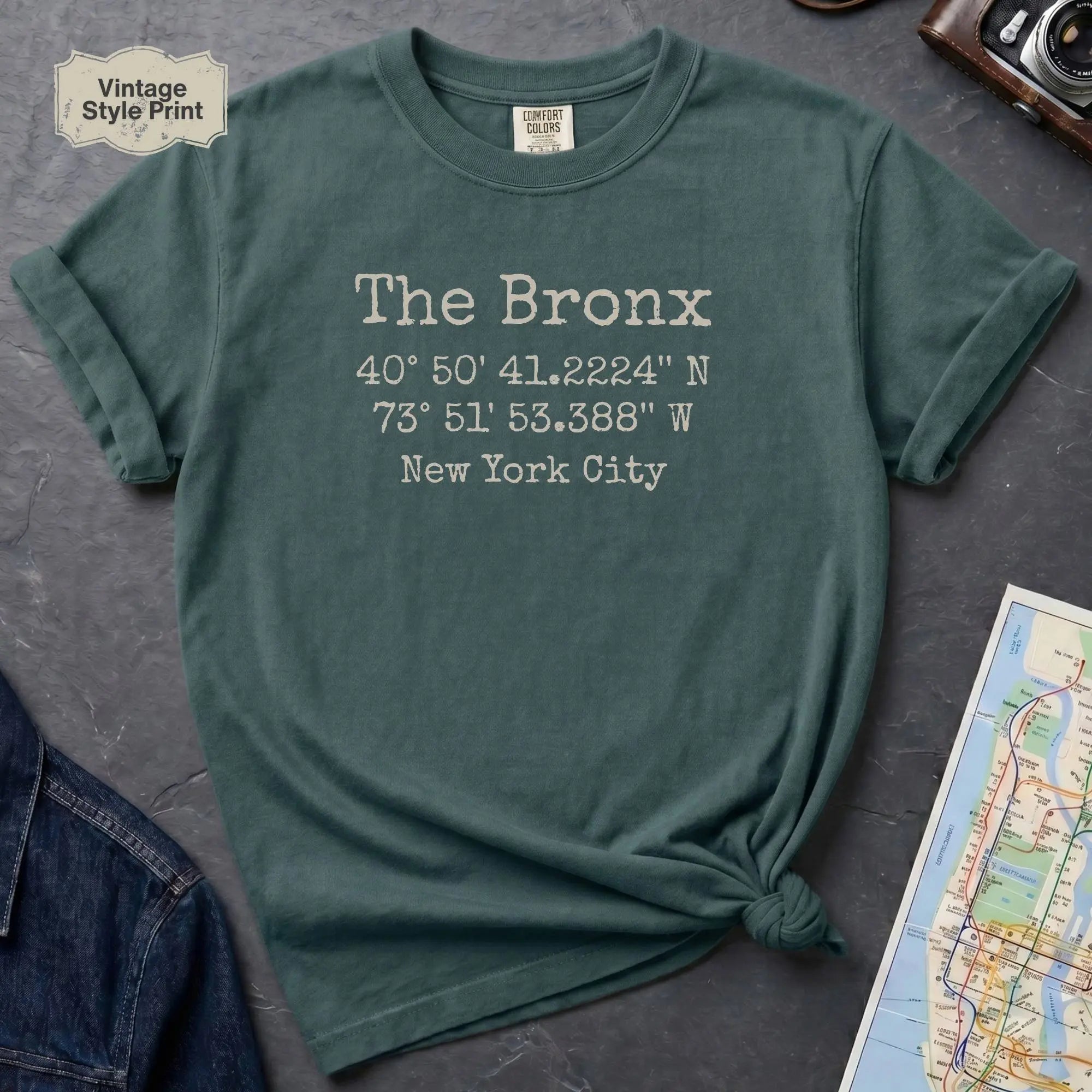 Blue spruce Comfort Colors t-shirt featuring The Bronx, NY coordinates and New York City text in a minimalist typewriter-style design.