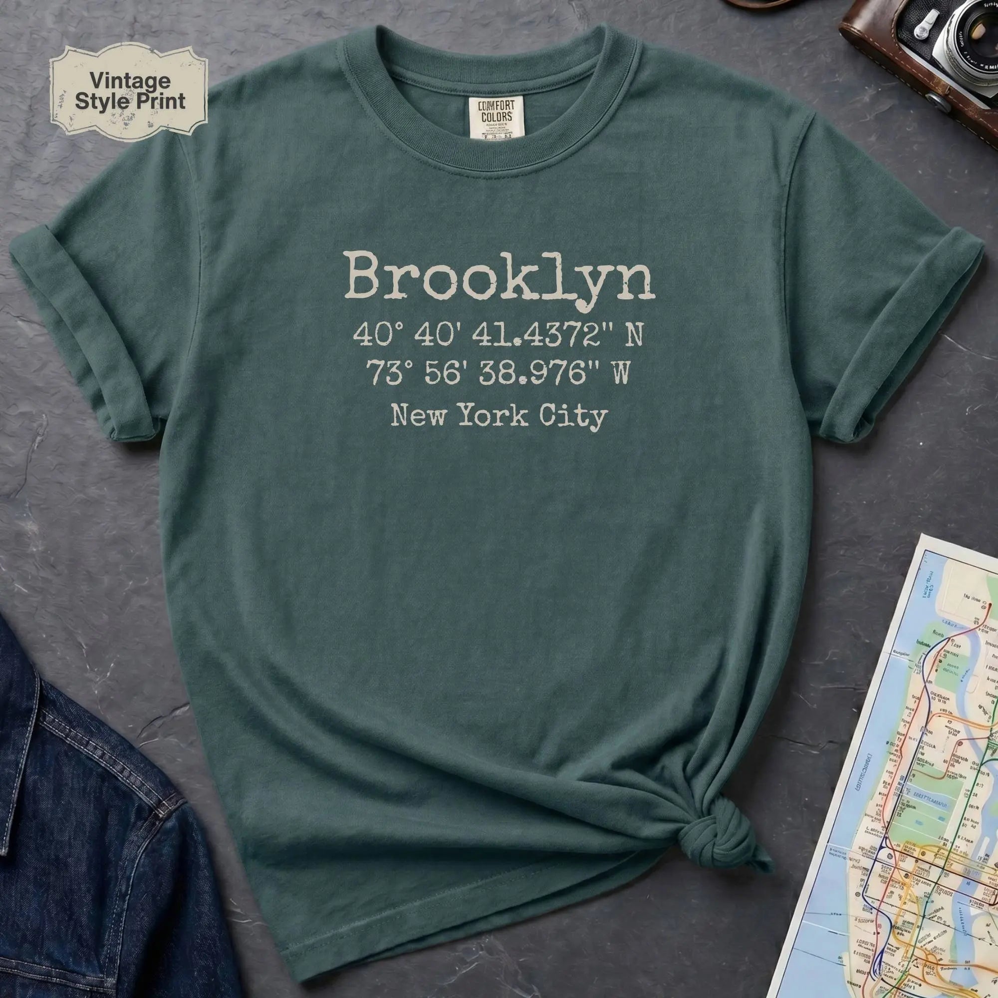 Blue Spruce Comfort Colors t-shirt featuring Brooklyn, NY coordinates and New York City text in a minimalist typewriter-style design.