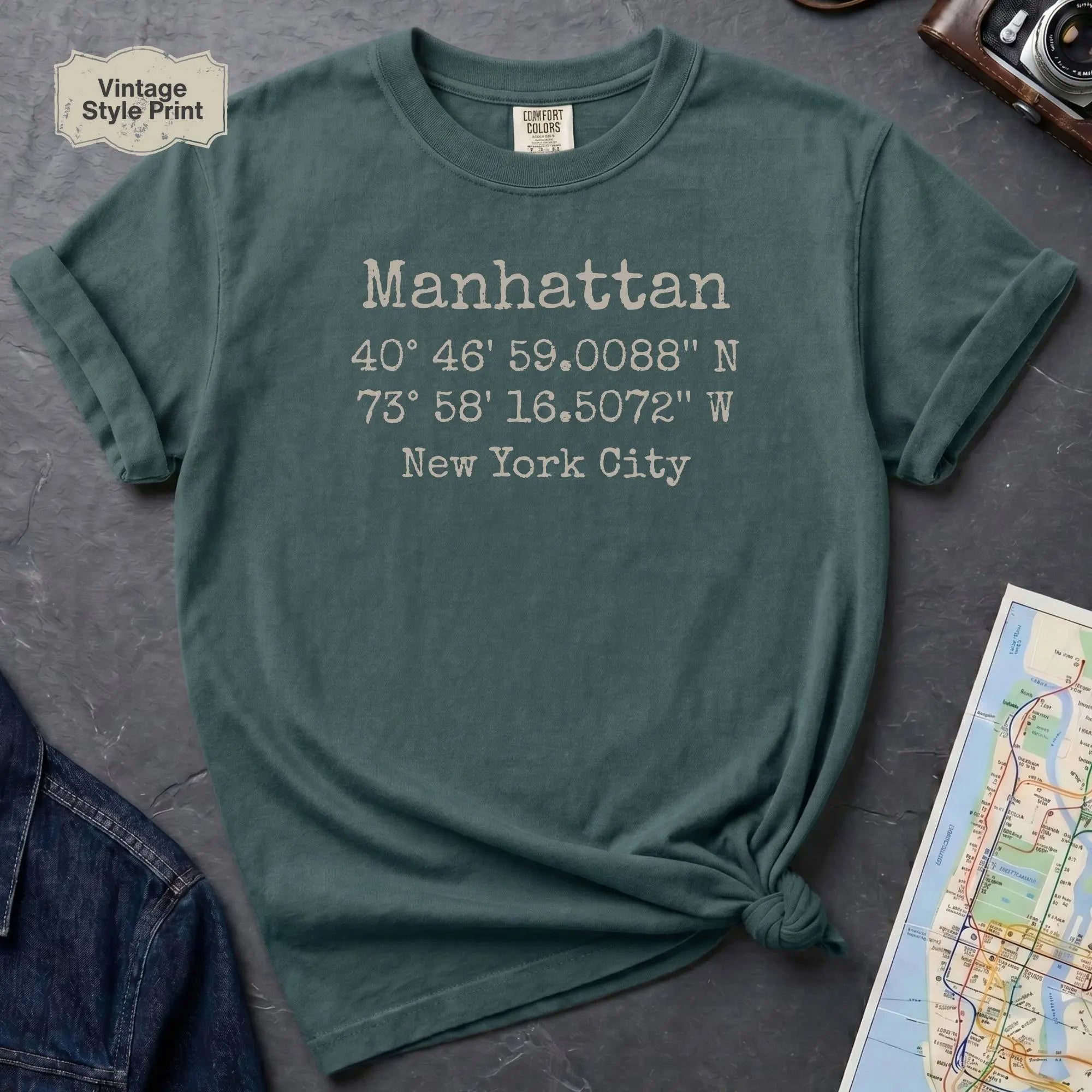 Blue spruce Comfort Colors t-shirt featuring Manhattan, NY coordinates and New York City text in a minimalist typewriter-style design.