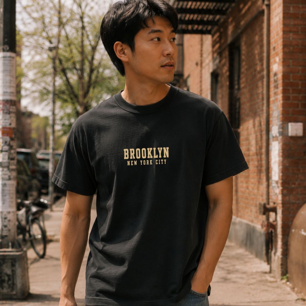 Man wearing a black Comfort Colors t-shirt with 'Brooklyn New York City' text on a street.