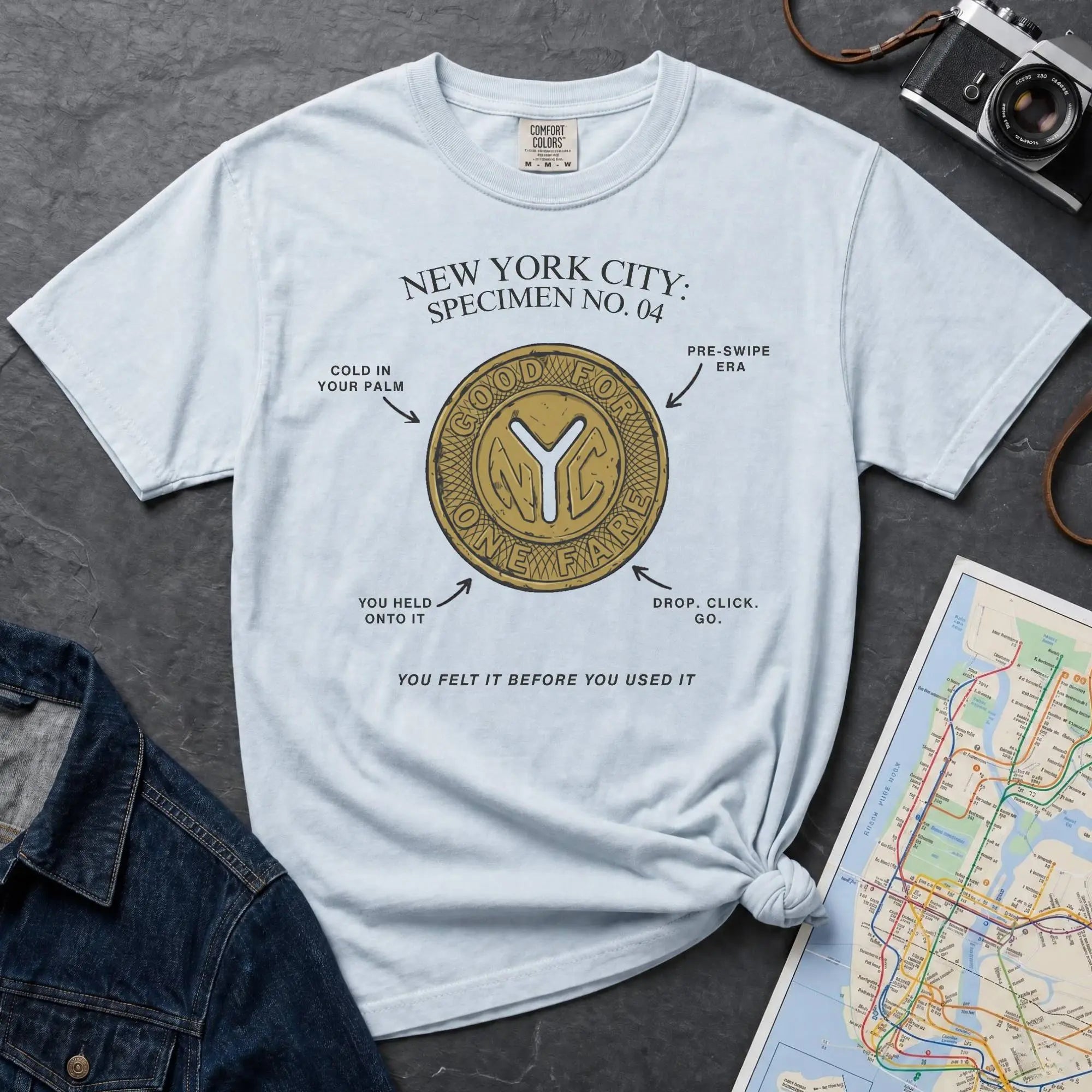 Light blue Comfort Colors t-shirt featuring a vintage New York City subway token graphic with specimen-style callouts and “You felt it before you used it” text.