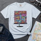 Light Blue t-shirt with a colorful graphic design featuring a breakdancer and text on a dark surface with a denim jacket and a map.