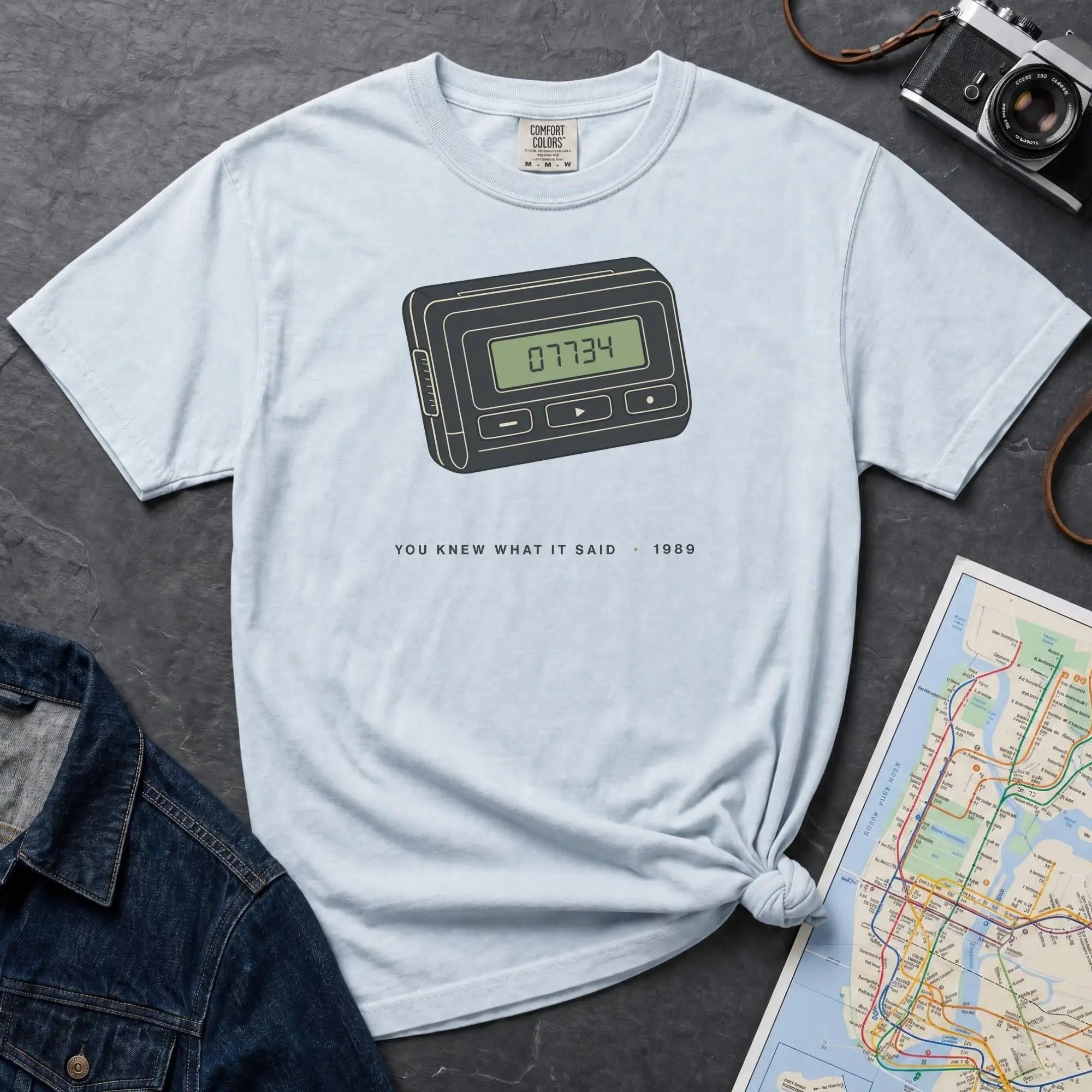 Light blue Comfort Colors t-shirt featuring a retro pager graphic with “07734” on the screen and “You knew what it said • 1989” text.