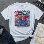 Light blue Comfort Colors t-shirt featuring a colorful NYC graffiti-style New York graphic with a young street artist holding a spray paint can