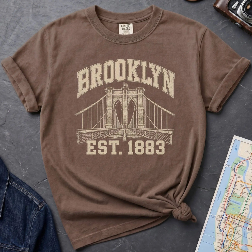 Brown Comfort Colors t-shirt featuring a vintage Brooklyn Bridge graphic with bold Brooklyn text and “Est. 1883” lettering.