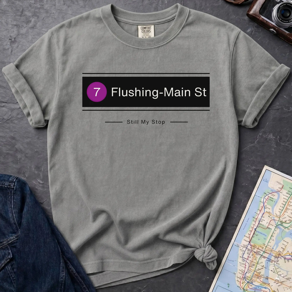 Granite colored t-shirt with 'Flushing-Main St' design on a dark surface with jeans and a map.