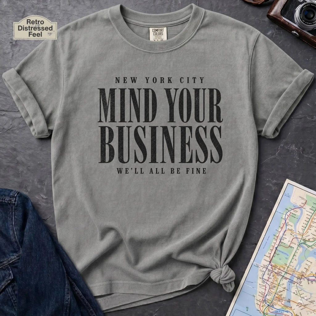 Granite colored Comfort Colors t-shirt featuring bold New York City “Mind Your Business, We’ll All Be Fine” text in a vintage black typography design.