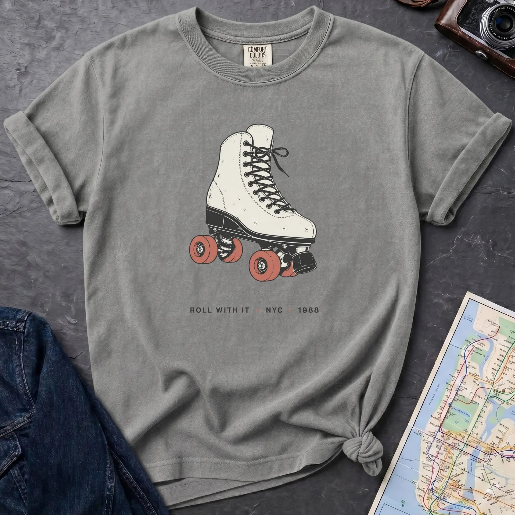 Granite colored Comfort Colors t-shirt featuring a vintage roller skate graphic with “Roll With It • NYC • 1988” text.