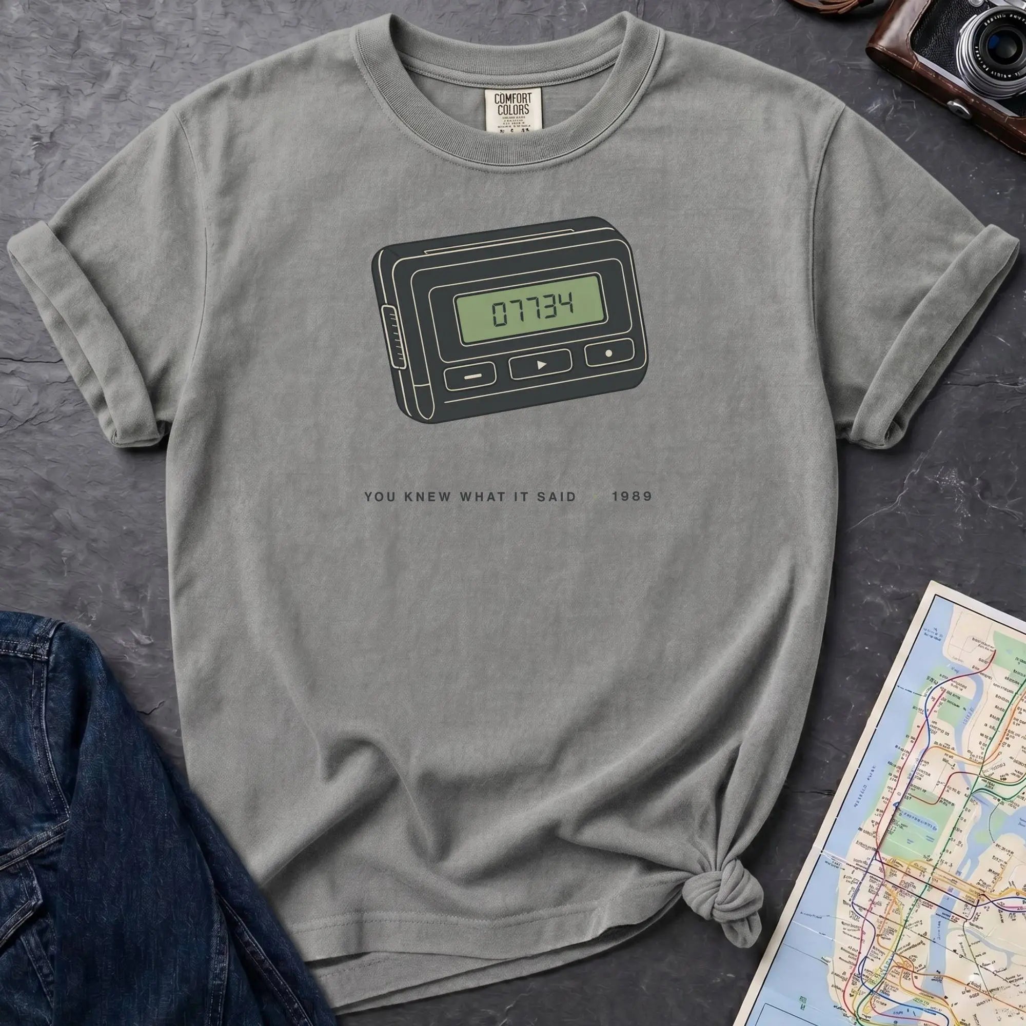 Granite colored Comfort Colors t-shirt featuring a retro pager graphic with “07734” on the screen and “You knew what it said • 1989” text.