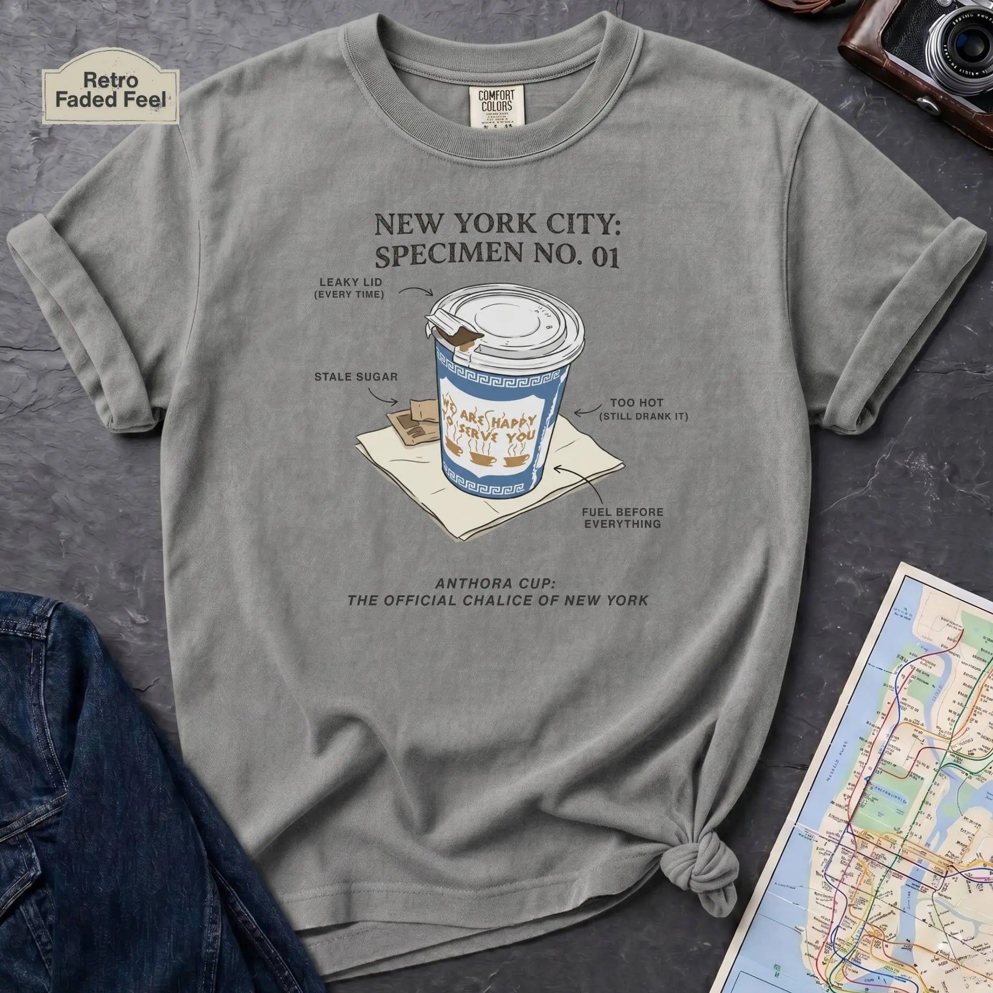Granite colored Comfort Colors t-shirt featuring a vintage New York City Anthora coffee cup graphic with specimen-style callouts and “The Official Chalice of New York” text.