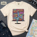 Ivory t-shirt with a colorful graphic design featuring a breakdancer and text on a dark surface with a denim jacket and a map.