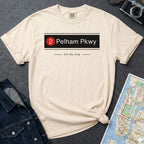 Ivory t-shirt with '2 Pelham Pkwy Still My Stop' design on a dark surface with denim jacket and map.