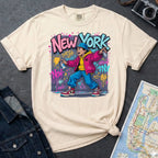 Ivory Comfort Colors t-shirt featuring a colorful NYC graffiti-style New York graphic with a young street artist holding a spray paint can