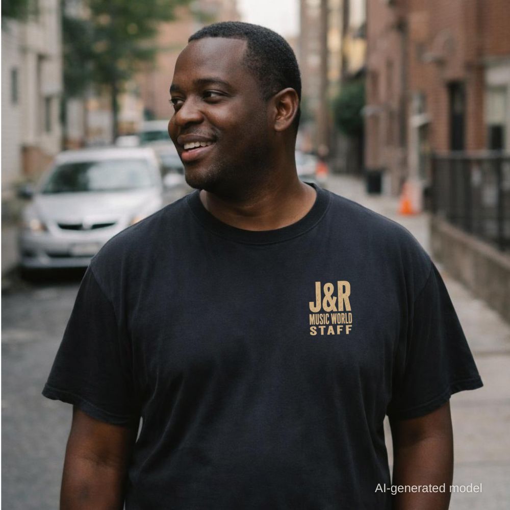 A man wearing a Black Comfort Colors T-shirt with off-white J&R Music World NYC small front chest staff print, standing on a city street.