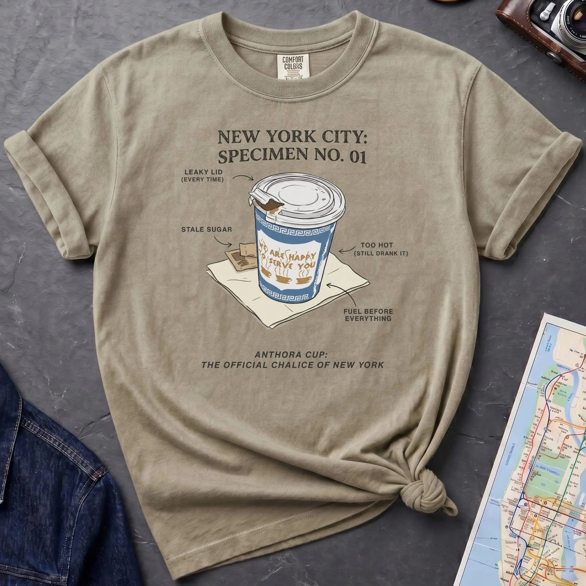 Khaki colored Comfort Colors t-shirt featuring a vintage New York City Anthora coffee cup graphic with specimen-style callouts and “The Official Chalice of New York” text.