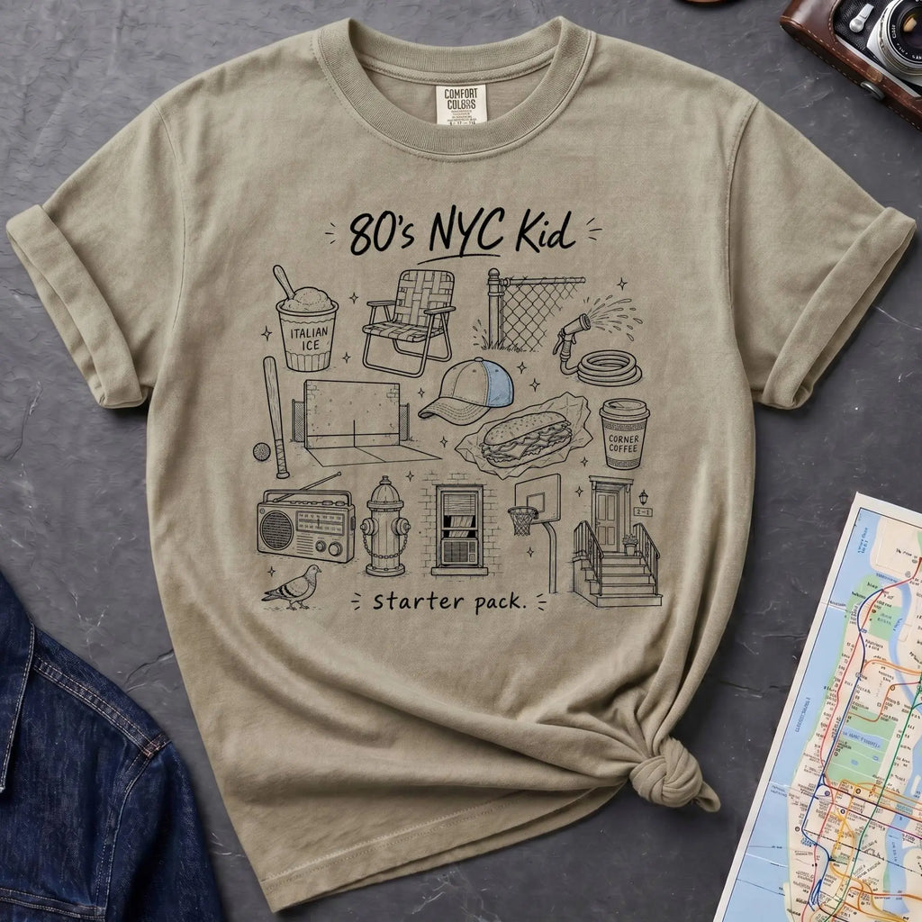 Khaki colored Comfort Colors t-shirt featuring an 80’s NYC Kid Starter Pack graphic with hand-drawn New York City icons including Italian ice, a radio, stoop steps, stickball, a fire hydrant, and a pigeon.