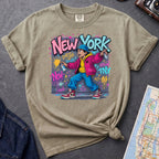 Khaki colored Comfort Colors t-shirt featuring a colorful NYC graffiti-style New York graphic with a young street artist holding a spray paint can