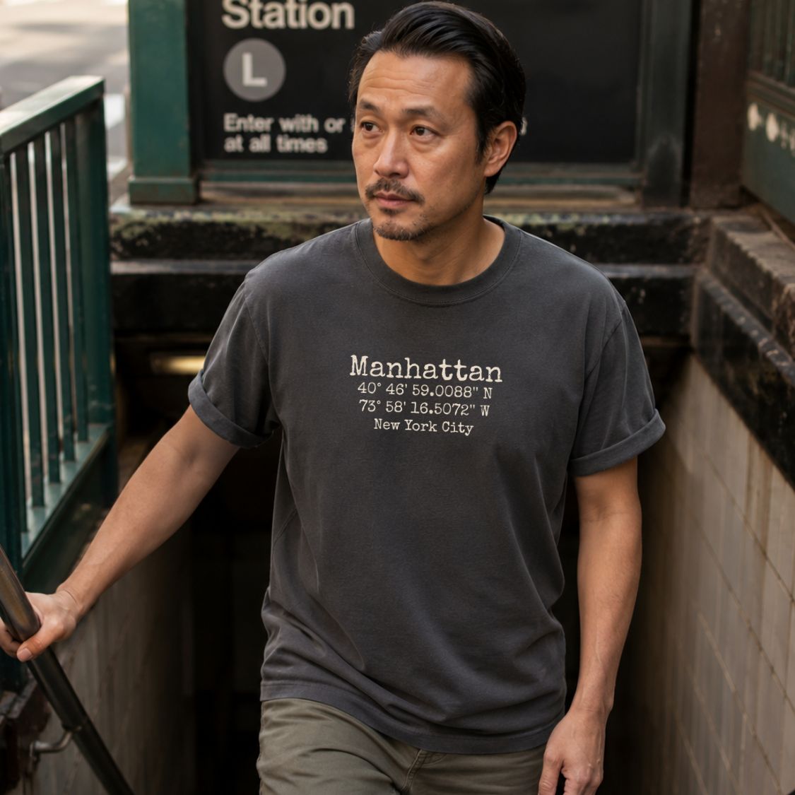 Man wearing a Pepper colored Comfort Colors t-shirt with Manhattan coordinates in a subway station