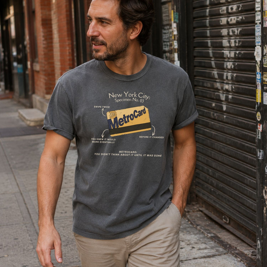 Man wearing a Pepper colored Comfort Colors t-shirt with a New York City MetroCard design on a city street.