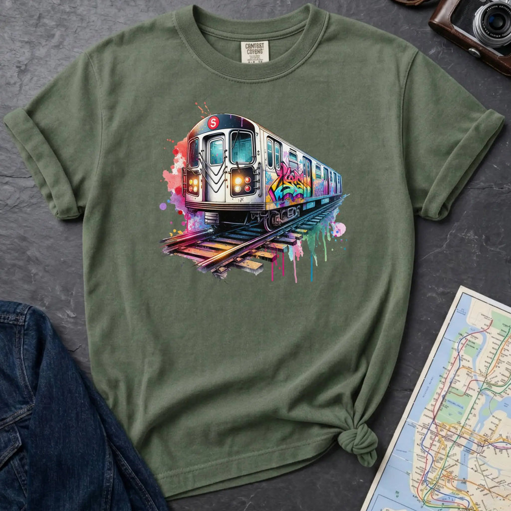 Moss green Comfort Colors t-shirt featuring a colorful NYC subway train graphic with graffiti-style paint details and bright street art accents.
