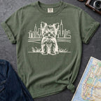 Moss green Comfort Colors t-shirt featuring a minimalist Yorkshire Terrier (Yorkie) illustration in front of the New York City skyline.