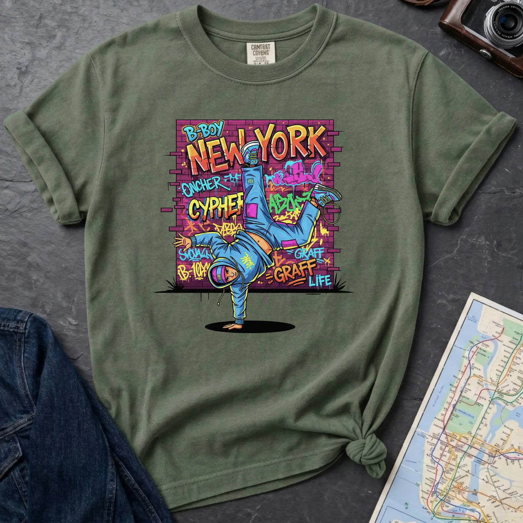 Moss green Comfort Colors t-shirt featuring a colorful B-Boy New York graphic with a breakdancer in front of a graffiti brick wall.