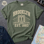 Moss green Comfort Colors t-shirt featuring a vintage Brooklyn Bridge graphic with bold Brooklyn text and “Est. 1883” lettering.