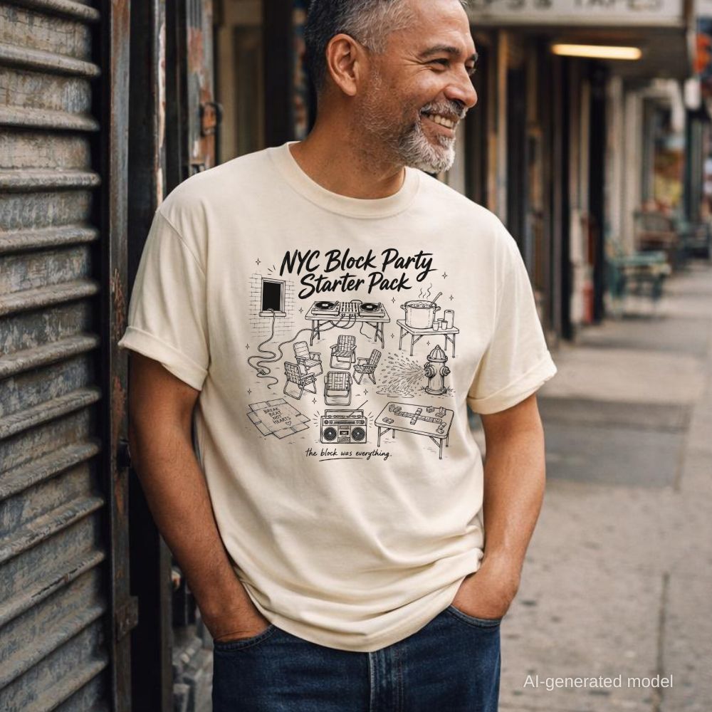 Man wearing an ivory Comfort Colors T-shirt with black NYC Block Party Starter Pack front print, standing in front of a closed store on a city street.