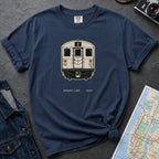 Navy t-shirt with a NYC subway train graphic on a dark surface with a map and a denim jacket.