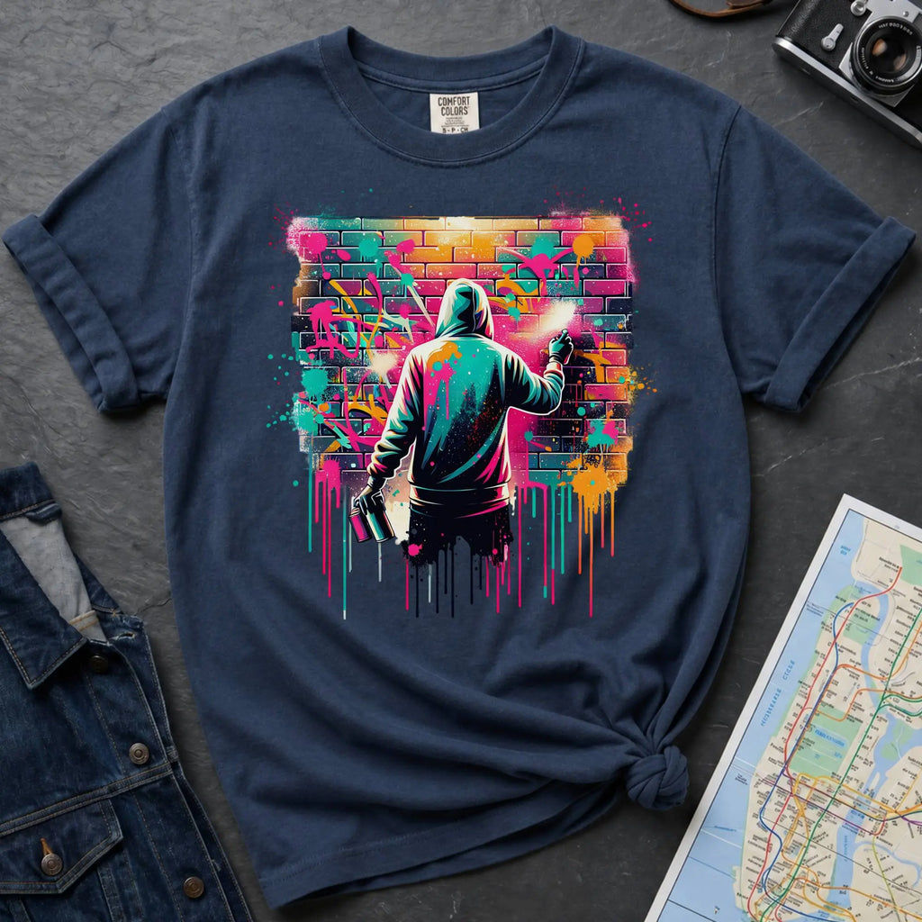 Navy t-shirt with a graphic of a person spray painting a colorful mural on a brick wall.