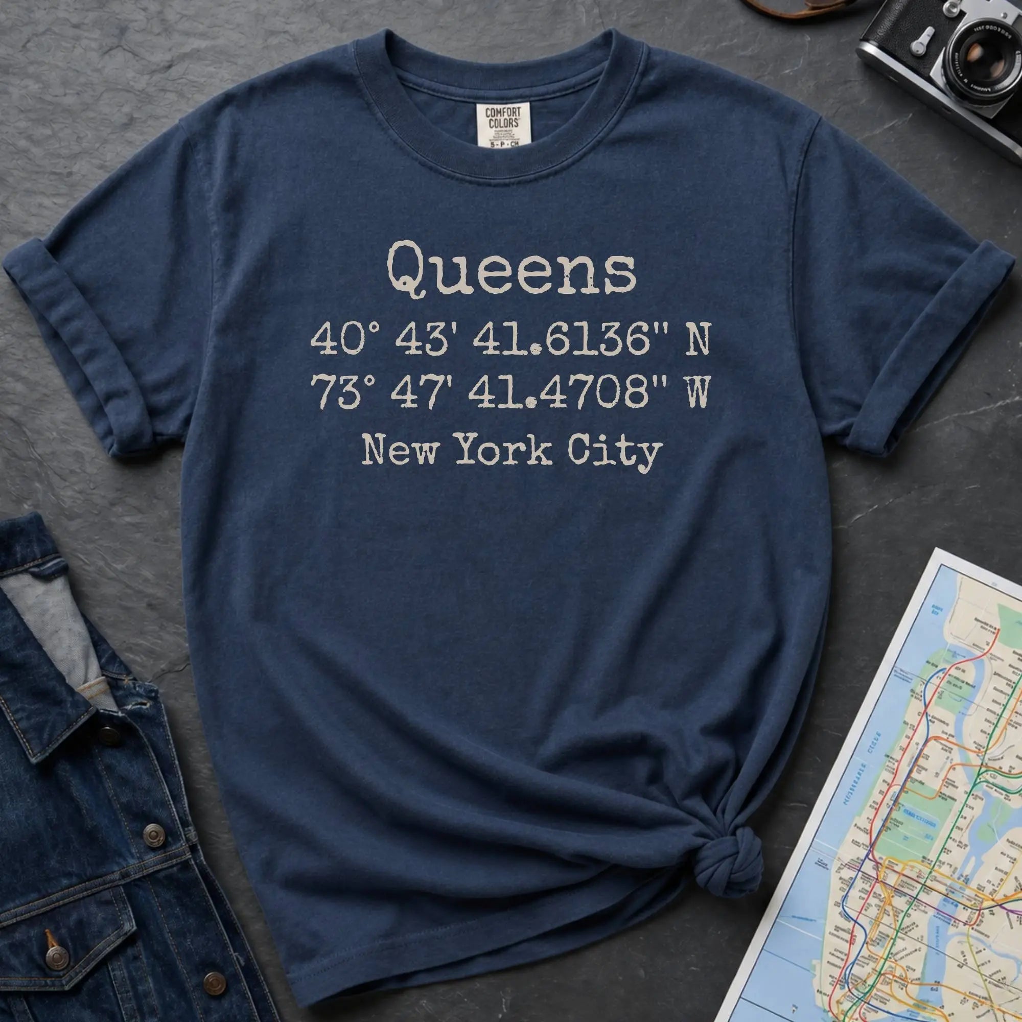 Navy Comfort Colors t-shirt featuring Queens, NY coordinates and New York City text in a minimalist typewriter-style design.