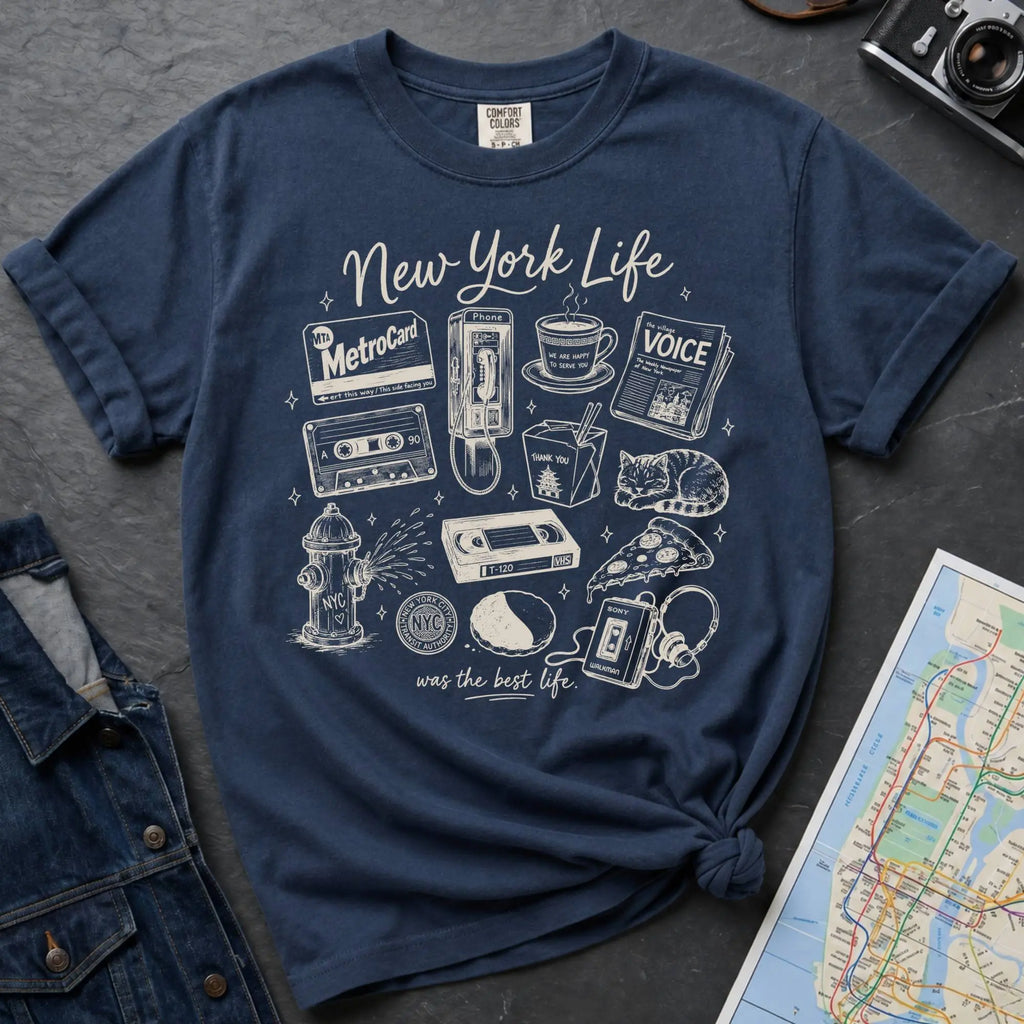 Navy Comfort Colors t-shirt featuring a New York Life Was the Best Life graphic with hand-drawn NYC nostalgia icons including a MetroCard, cassette tape, pay phone, coffee cup, newspaper, pizza slice, fire hydrant, Walkman, and bodega cat.