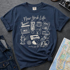 Navy Comfort Colors t-shirt featuring a New York Life Was the Best Life graphic with hand-drawn NYC nostalgia icons including a MetroCard, cassette tape, pay phone, coffee cup, newspaper, pizza slice, fire hydrant, Walkman, and bodega cat.
