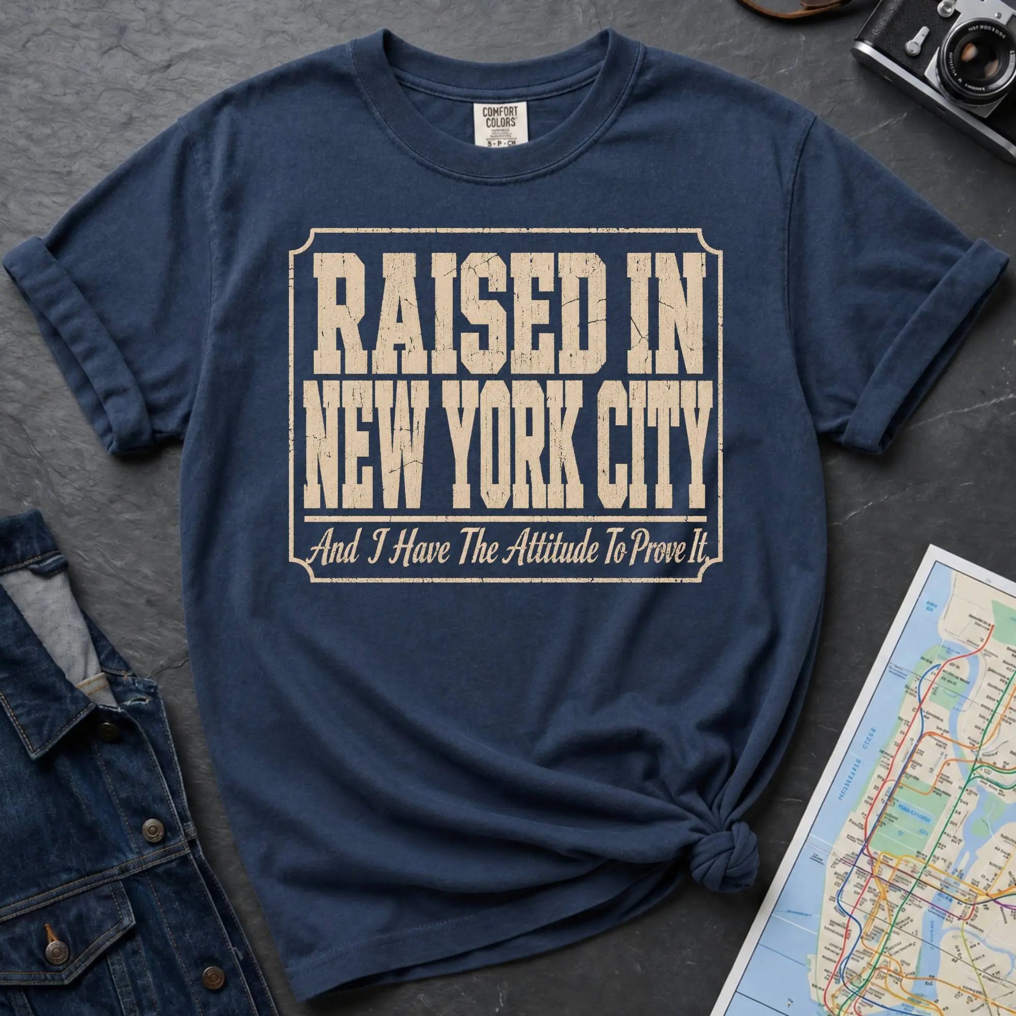 Navy Comfort Colors t-shirt featuring distressed vintage text that reads “Raised in New York City, And I Have the Attitude to Prove It.