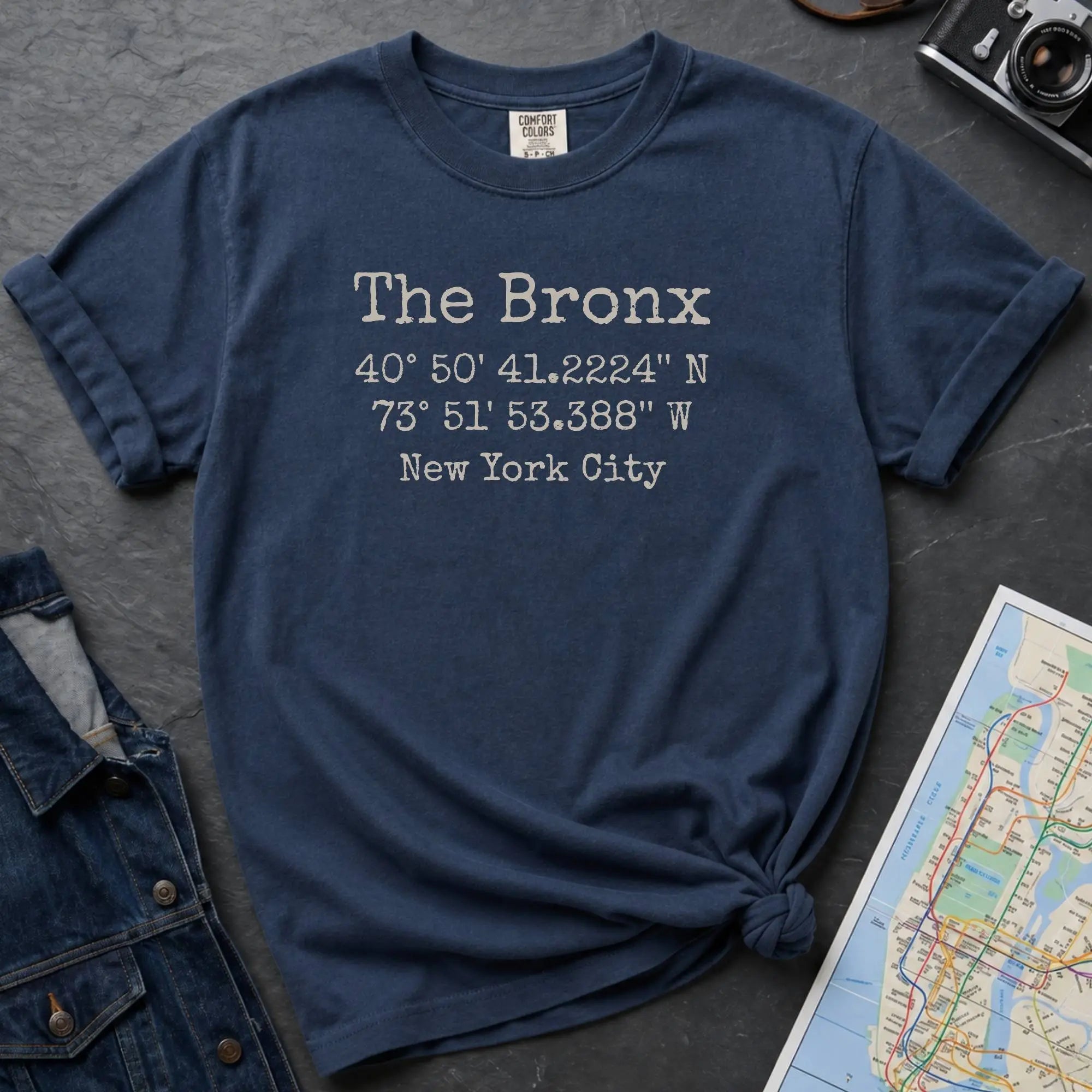 Navy Comfort Colors t-shirt featuring The Bronx, NY coordinates and New York City text in a minimalist typewriter-style design.
