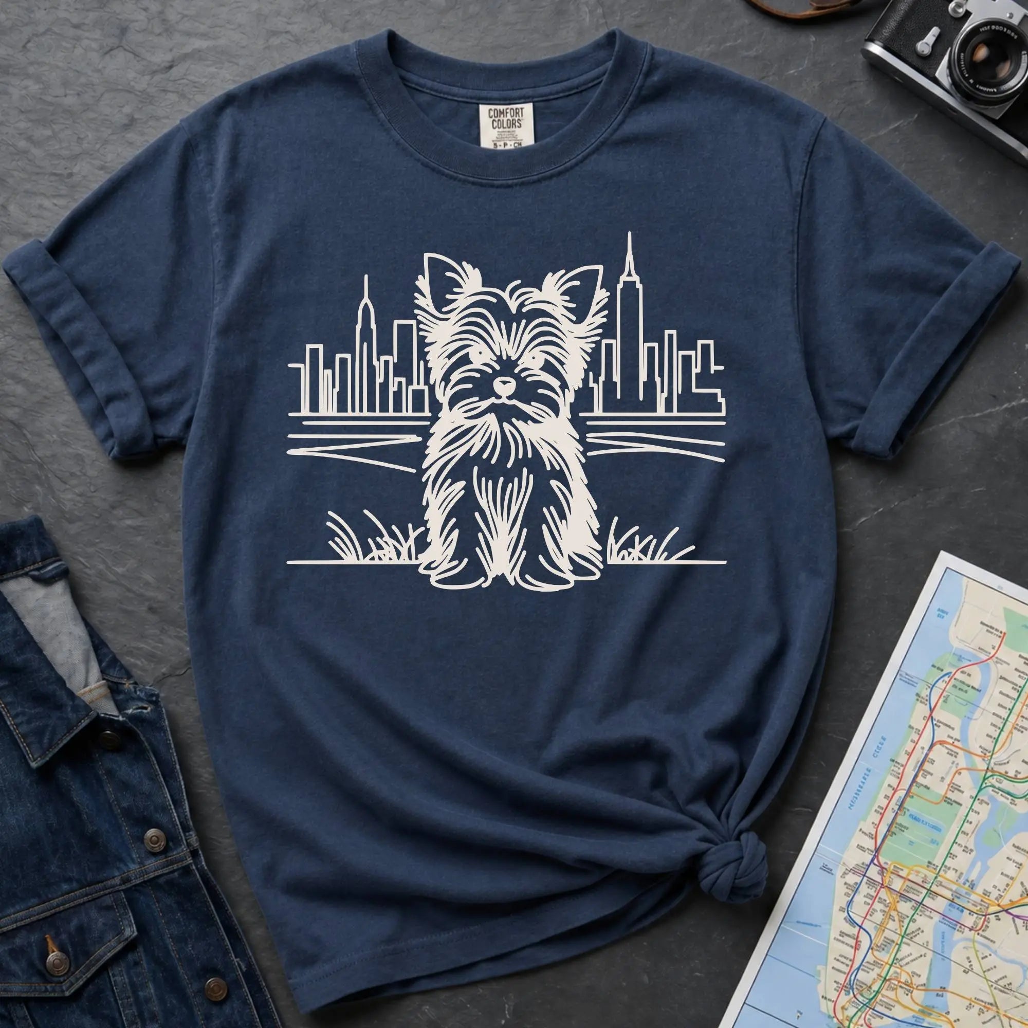 Navy Comfort Colors t-shirt featuring a minimalist Yorkshire Terrier (Yorkie) illustration in front of the New York City skyline.