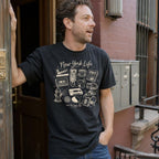 Man wearing a black t-shirt with 'New York Life' graphic design, standing on a street.