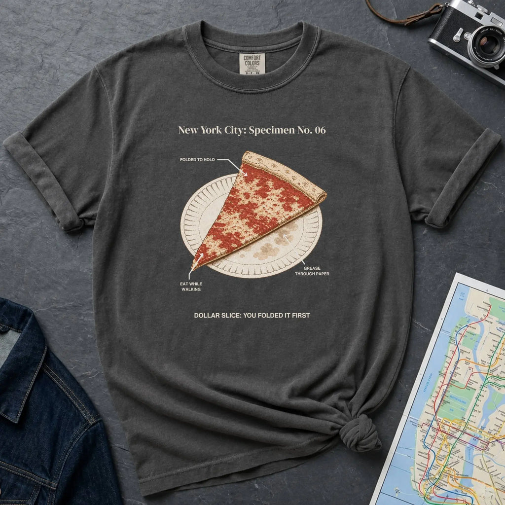 Pepper colored Comfort Colors t-shirt featuring a vintage New York City dollar slice pizza graphic with specimen-style callouts and a folded slice on a paper plate.
