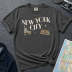 Pepper colored t-shirt with 'New York City' text and a roller skate and boom box on a dark surface with a map and camera.