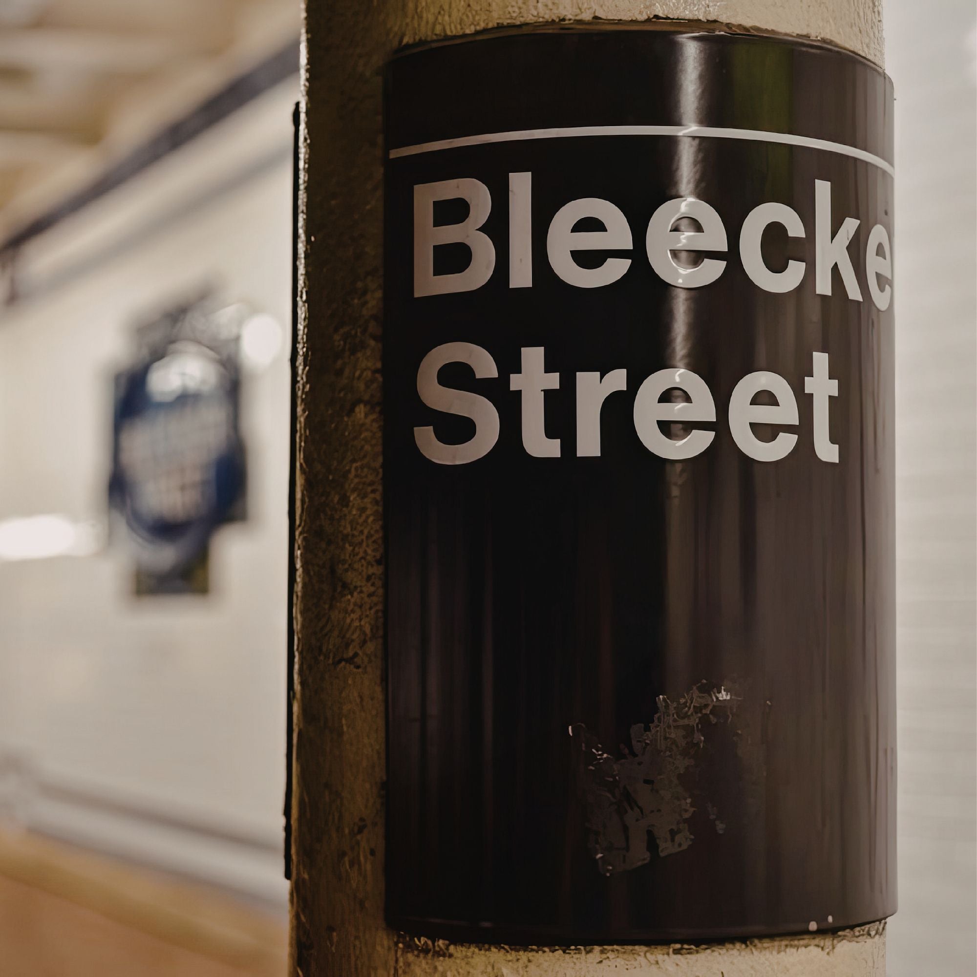 Subway sign reading 'Bleecker Street' on a pole with a blurred background