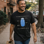 Man wearing a black Comfort Colors t-shirt with a blue Quarter Water bottle graphic and text, walking down a street.