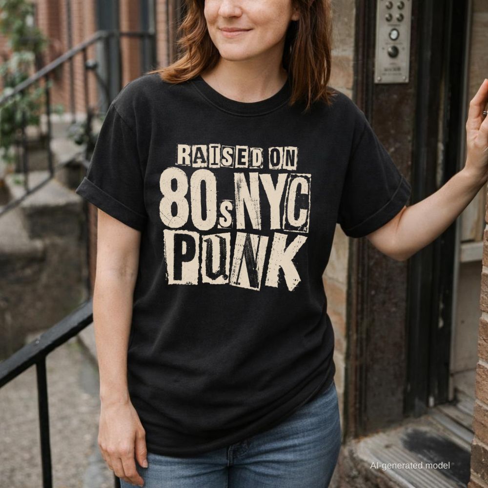 Woman wearing a black Comfort Colors t-shirt with bold distressed ransom note style lettering reading "Raised on 80s NYC Punk" in mixed fonts and sizes, black ink on ivory, xerox zine aesthetic, while standing at the front door of a brownstone. 