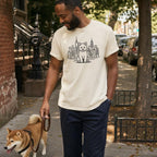 Man walking down a street with a Shiba Inu wearing an Ivory Colored Comfort Colors t-shirt featuring a minimalist Shiba Inu graphic in front of the New York City skyline. 