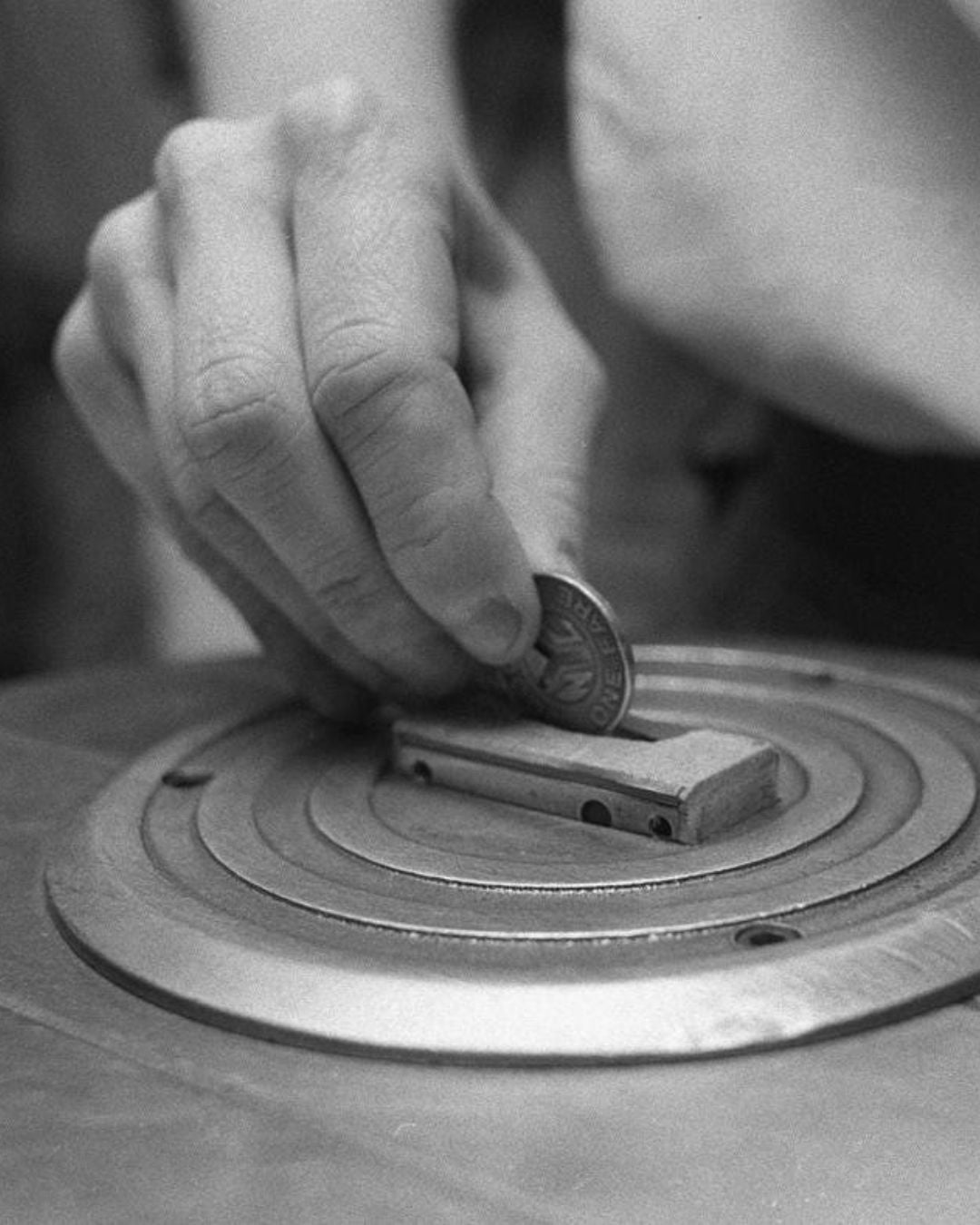 Person placing a using a NYV vintage token into the slot of a subway turnstile. 