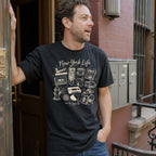 Man wearing a black t-shirt with 'New York Life' graphic design, standing on a street.