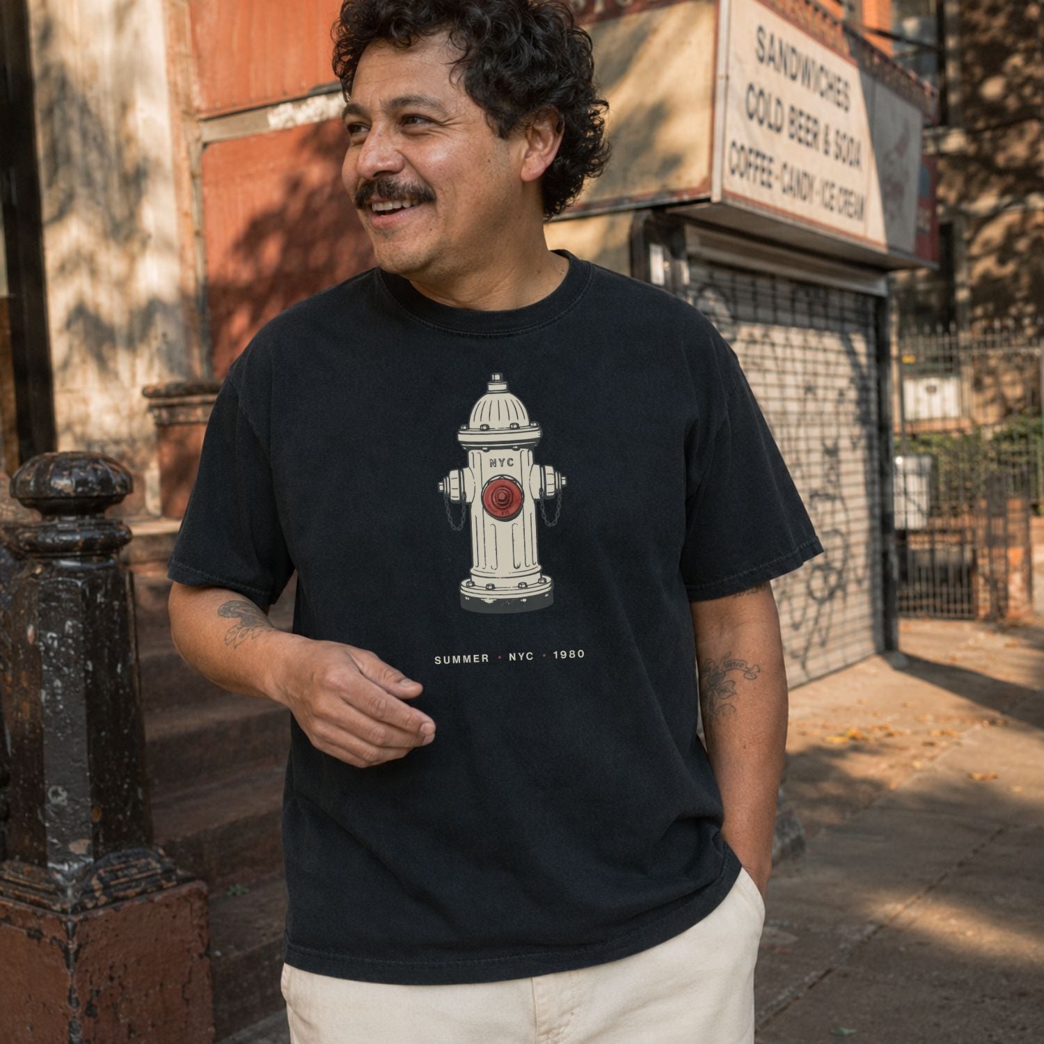 Man wearing a black t-shirt with a fire hydrant design, standing on a street.