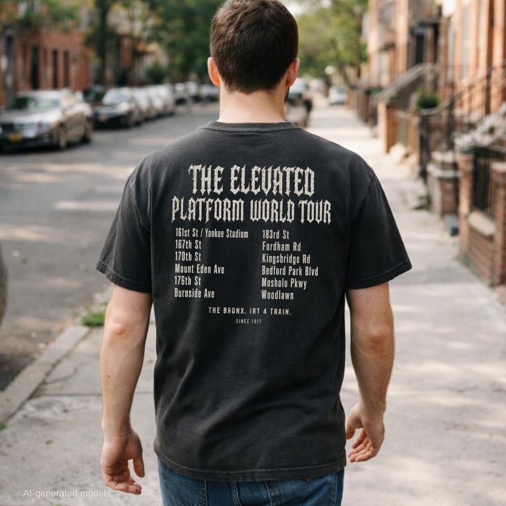 Man wearing a Black Comfort Colors t-shirt with Back print listing all 12 stops on the 4 train from 161st St/Yankee Stadium to Woodlawn with "The Bronx. IRT 4 Train. Since 1917" at the bottom, while walking down a city sidewalk.