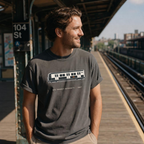 Man wearing a t-shirt with a train design on a NYC subway platform.